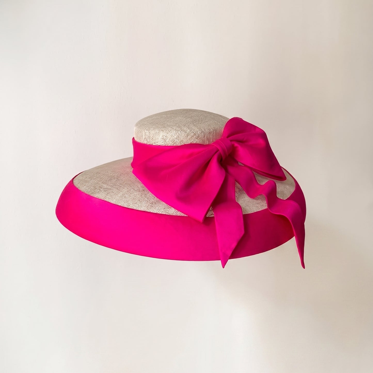 Natural sinamay hat featuring a vibrant fuchsia Dupioni silk bow and brim binding.
