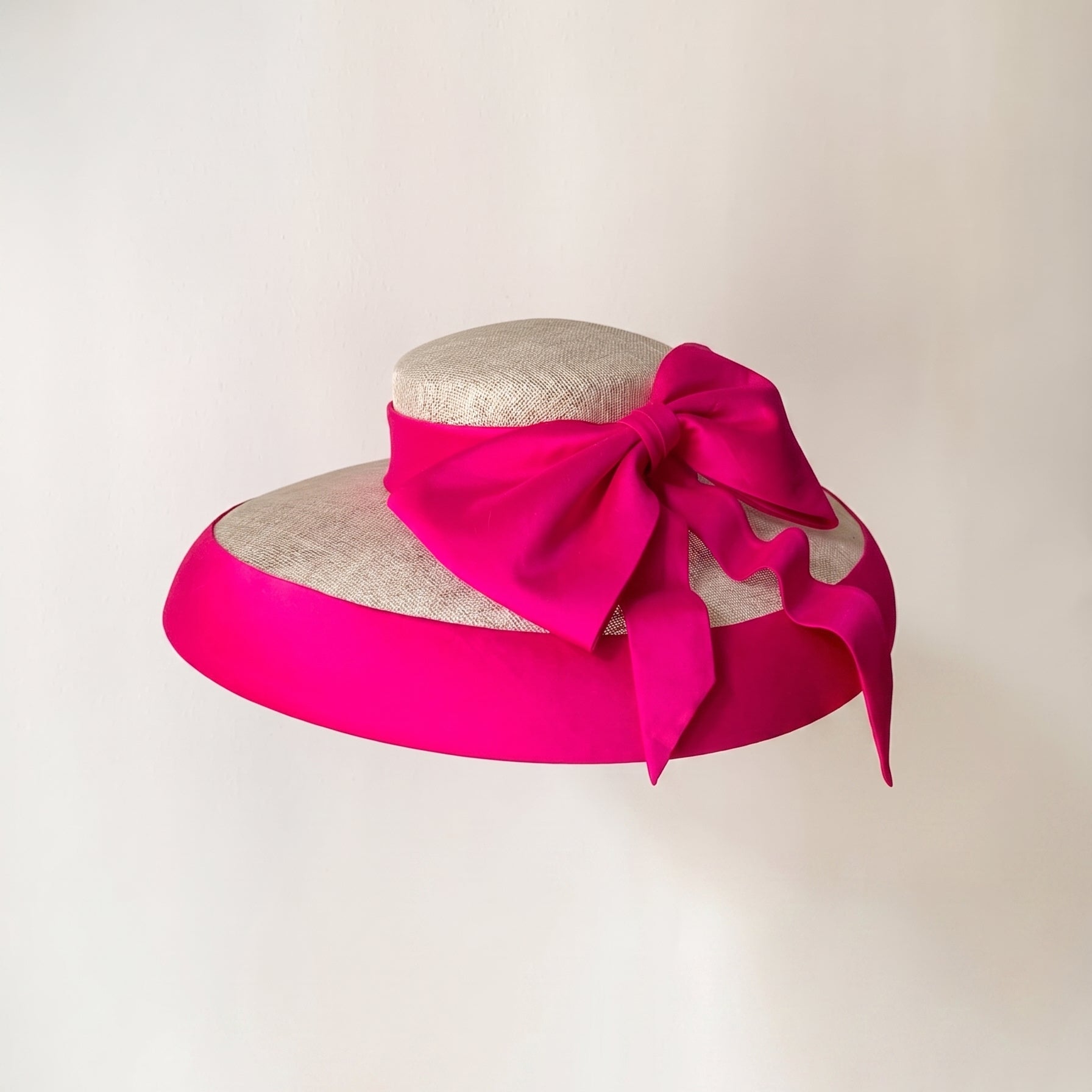 Natural sinamay hat featuring a vibrant fuchsia Dupioni silk bow and brim binding.